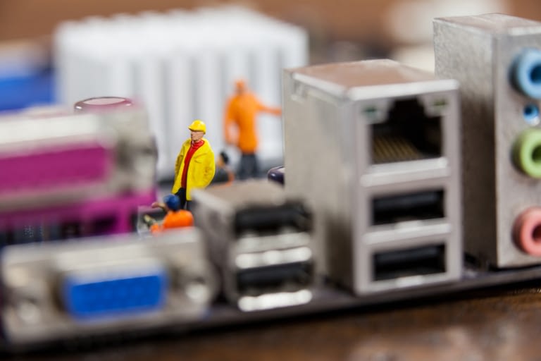 Miniature Workers Working On Chip Of Motherboard